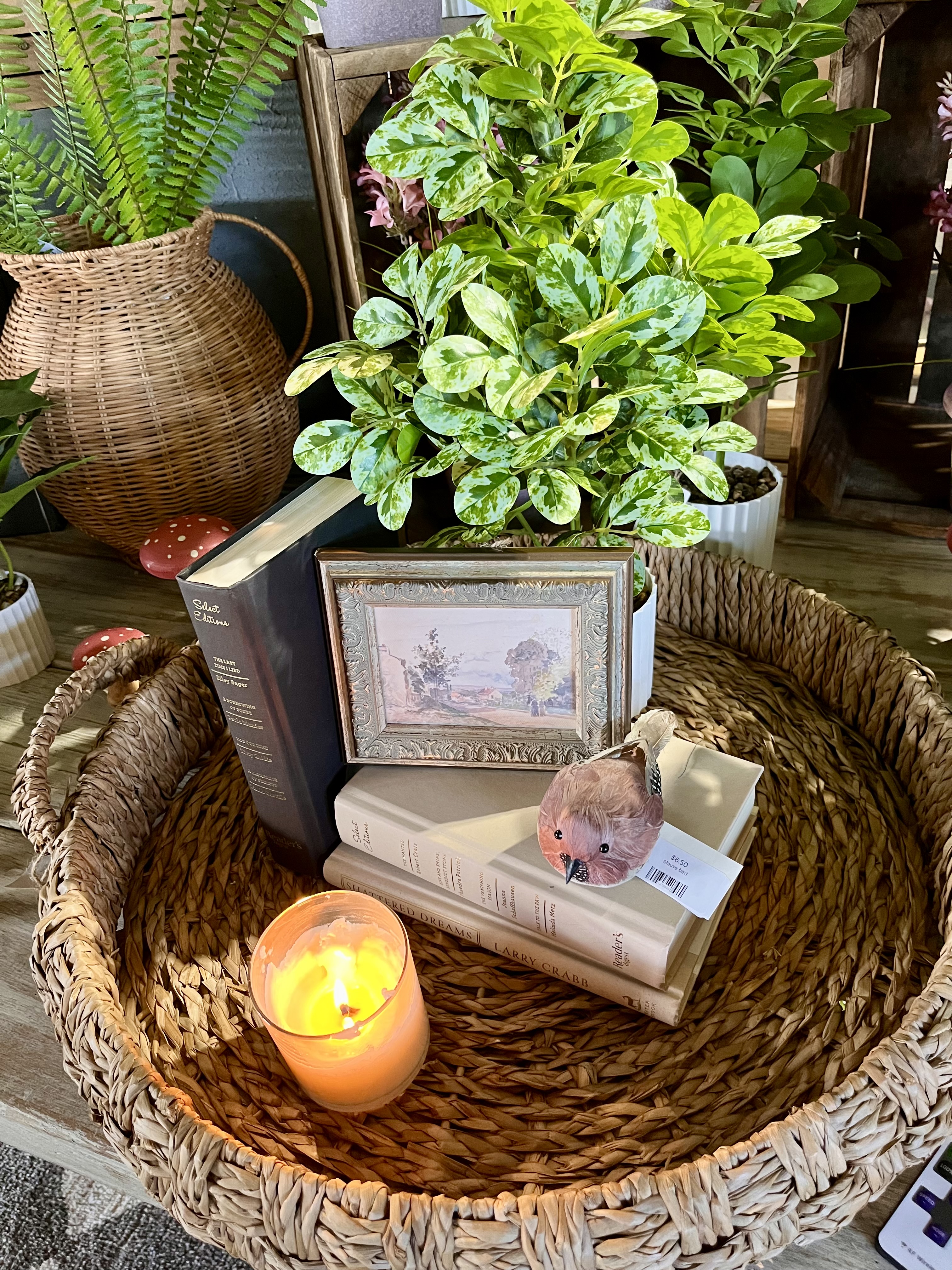 A styled basket with plant, book, and lit candle at Millie's